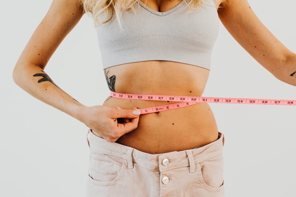 Woman in Loose Denim Measuring Her Waistline